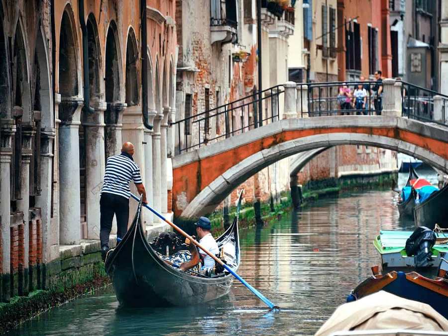 Gondola passing under a small Venice bridge on a canal